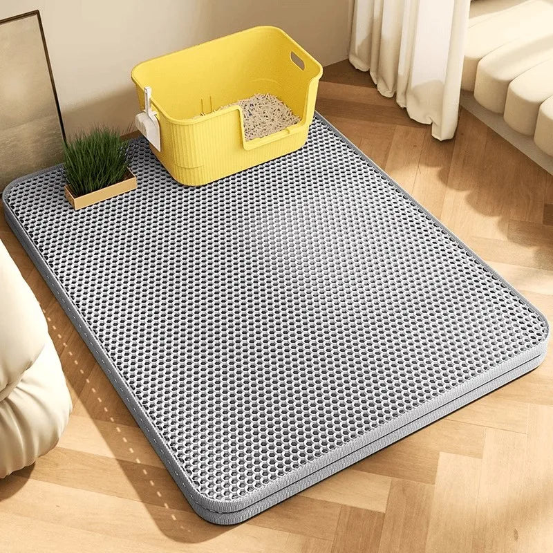 Gray pet mat on a wooden floor with a yellow litter box in the corner.