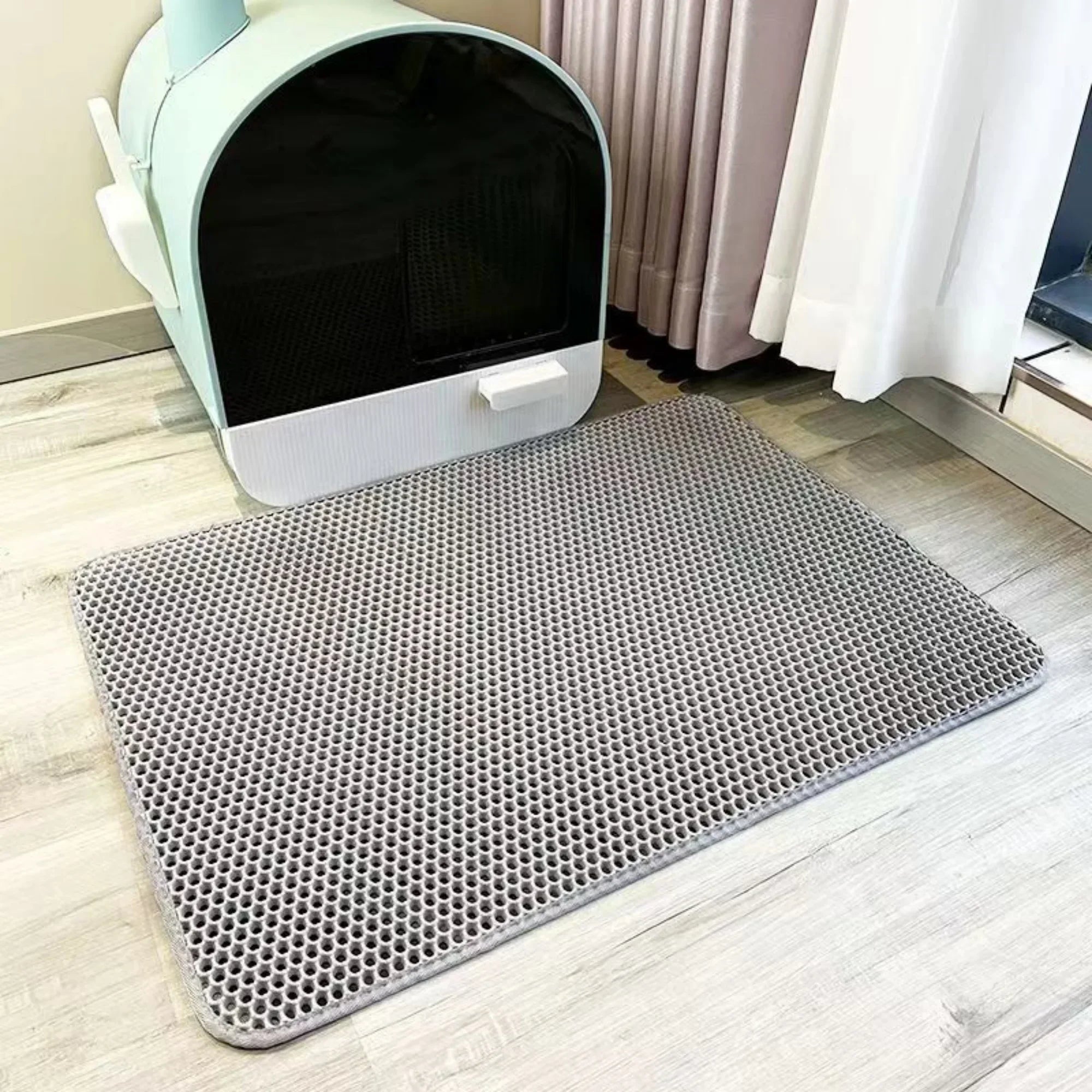 Gray mat with holes in front of a white pet bed on a wooden floor.