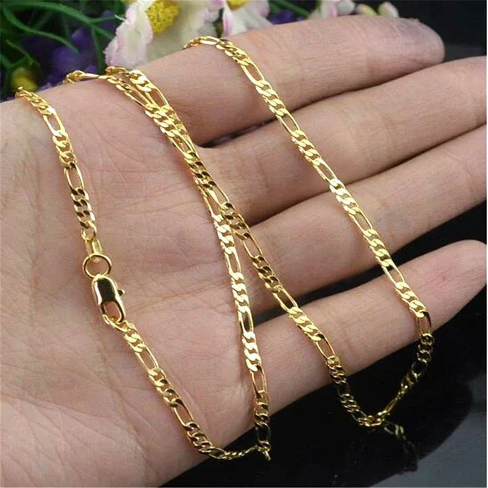 Gold chain necklace on a hand with a blurred floral background