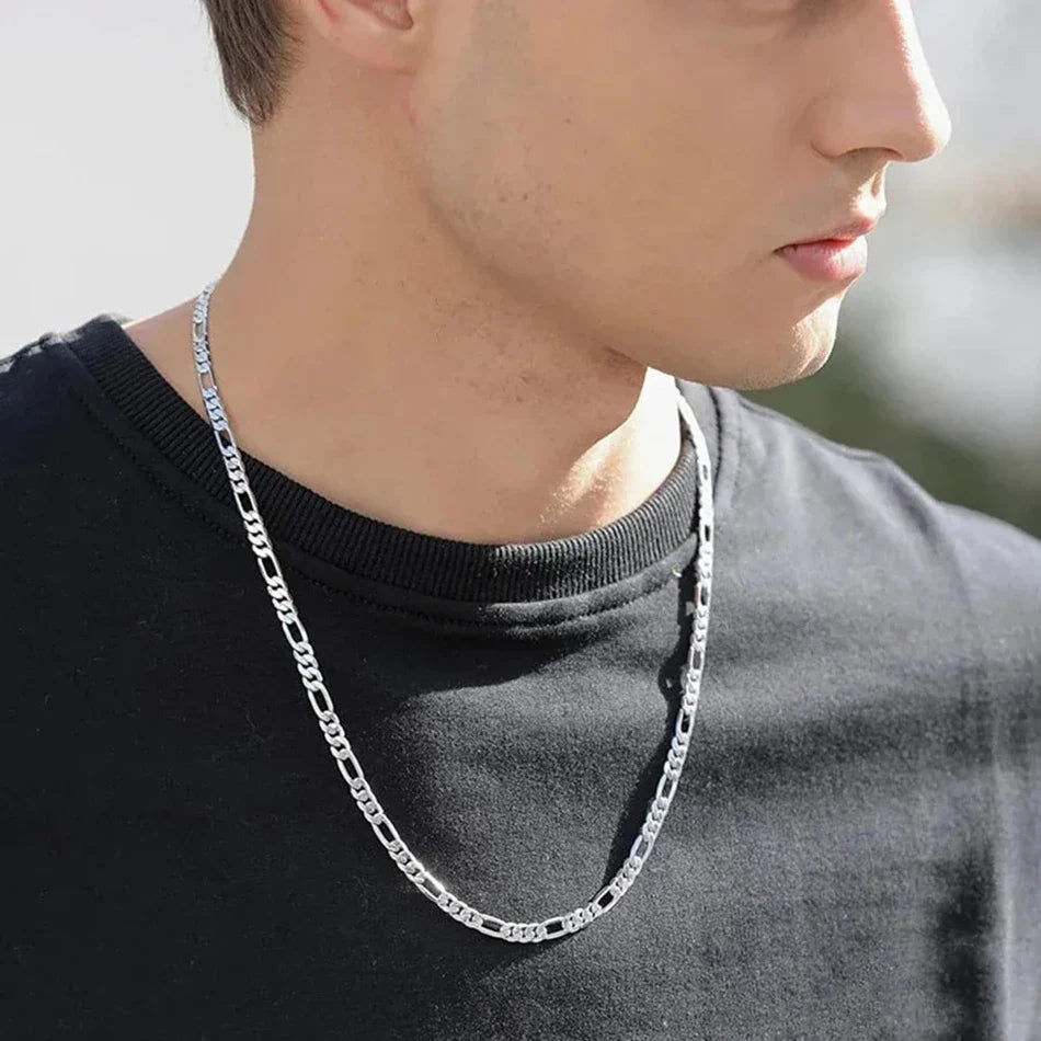 Man wearing a silver chain necklace against a neutral background