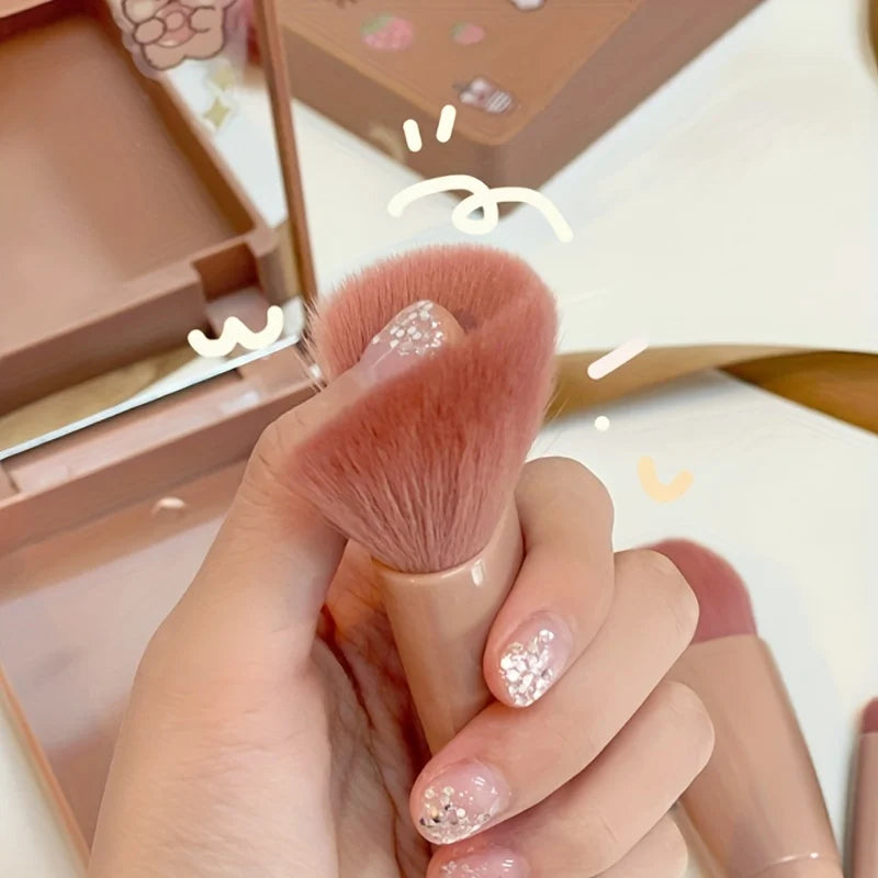Makeup brush held by a hand with decorative nails, against a blurred makeup product background.