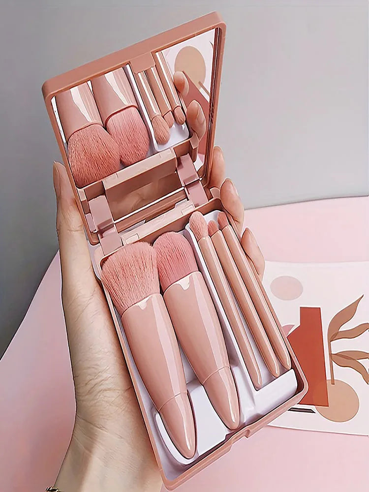 Makeup set with lipsticks and brushes in a pink case held by a hand.