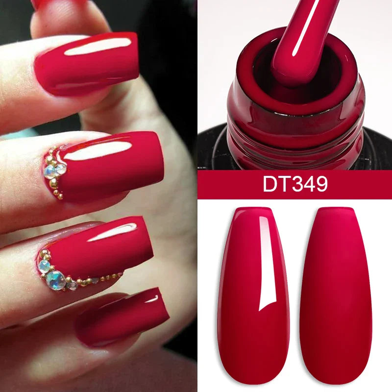 Red nail polish with a bottle and nails decorated with gemstones.