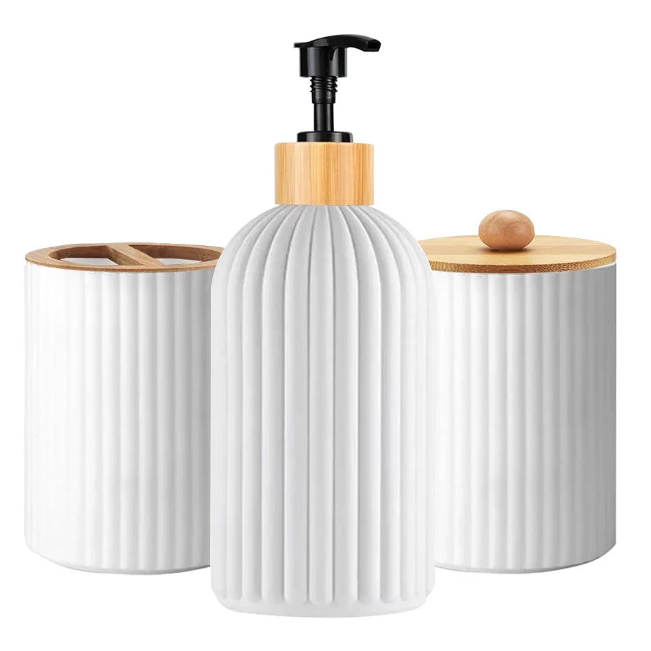 Set of three white ceramic containers with wooden lids and a pump on a white background