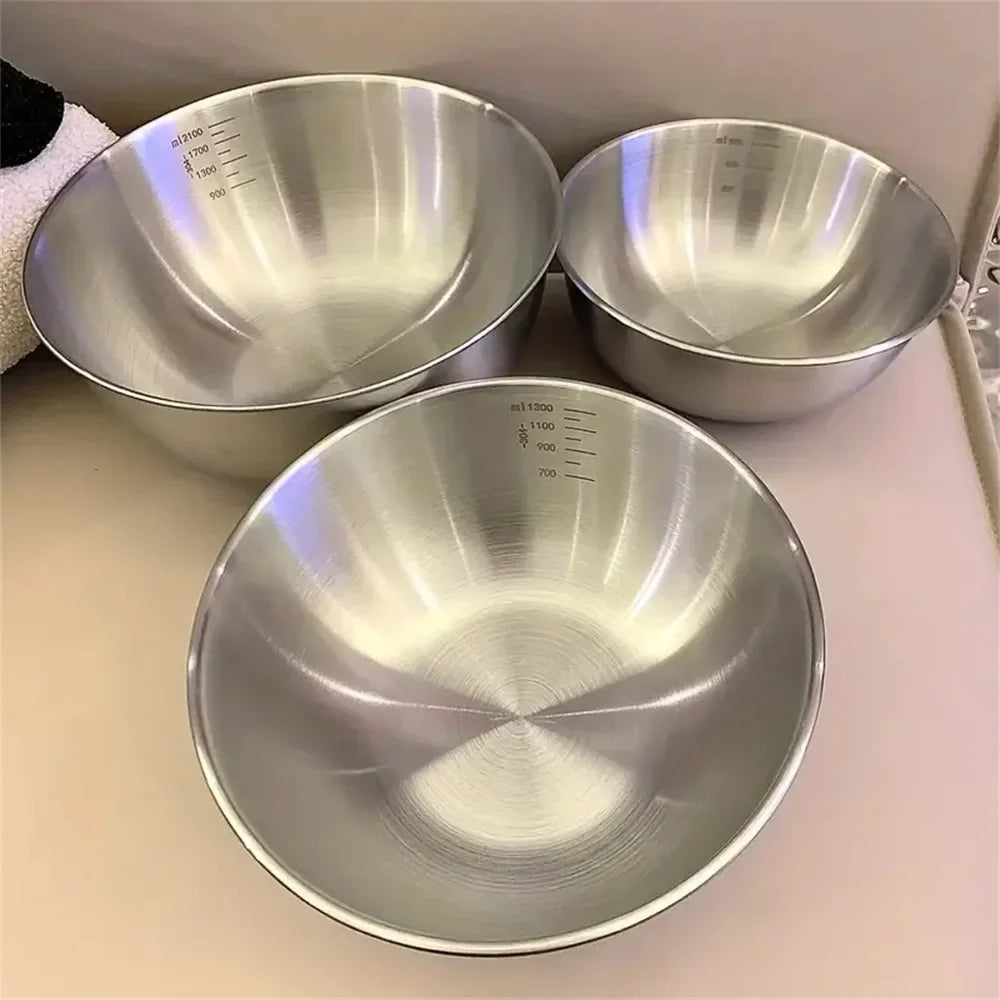 Three stainless steel bowls of different sizes on a light surface.