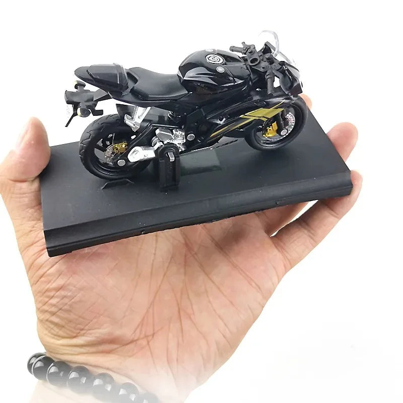 Black motorcycle model on a black stand held in a hand against a white background