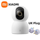 Xiaomi smart camera with UK plug adapter on a white background