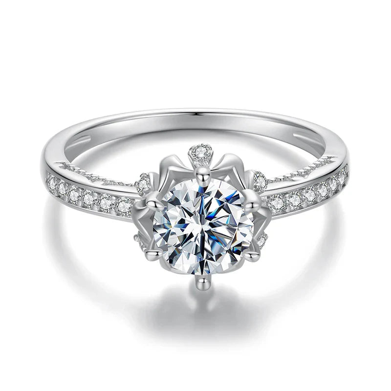 Silver ring with a large diamond and smaller diamonds on the band against a white background